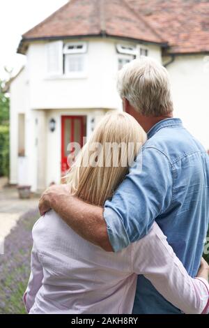 Vue arrière du Couple Standing In Garden Regarder Maison de rêve en campagne Banque D'Images