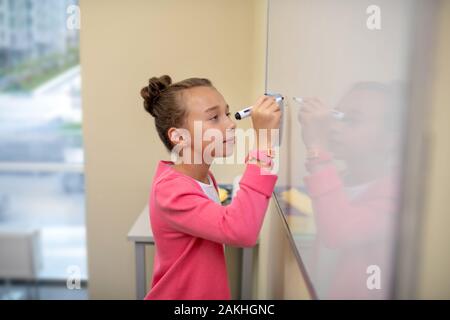 Rédaction de lettres méticuleusement fille sur le tableau blanc Banque D'Images