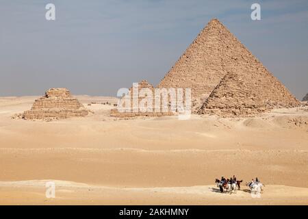 Les gens monter à cheval à travers le désert de sable sur le plateau près de Gizeh Les pyramides de l'Égypte Banque D'Images