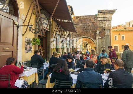 Les gens mangent à l'extérieur dans une trattoria typique à Ghetto, quartier juif de Rome, avec Portico d'Octavia (Portico di Ottavia) en arrière-plan Banque D'Images