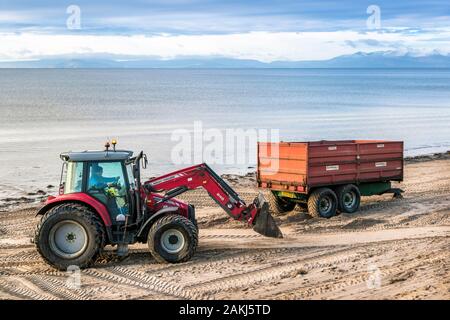 Tracteur et remorque étant utilisés pour nettoyer la pollution et déchets de la plage publique, Irvine, Ayrshire du Nord, Royaume-Uni Banque D'Images