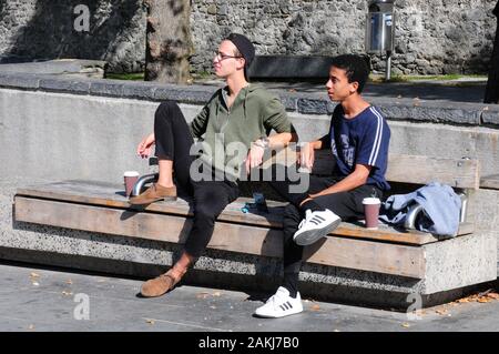 Deux jeunes hommes se détendant au soleil sur un banc public, Kilkenny. Avec permissionl. Banque D'Images