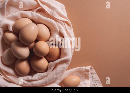 Oeufs frais sur un nid , sur un fond de papier brun. Brown oeufs biologiques dans une pile sur une serviette de cuisine. Voir ci-dessus des oeufs de pâques. L'alimentation en protéines. Banque D'Images