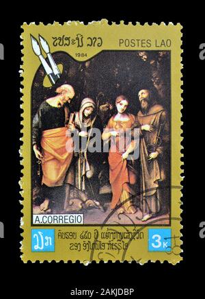 Timbre-poste annulé imprimé par le Laos, qui montre la peinture à des motifs religieux par Corregio, vers 1984. Banque D'Images