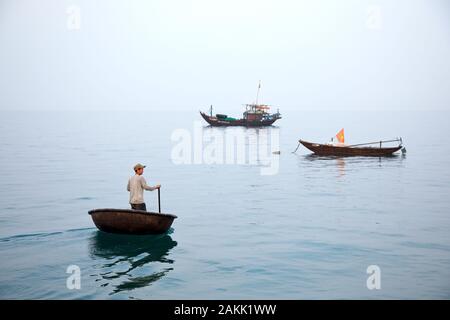 Pêcheur vietnamien travaille dans son coracle de son bateau de pêche plus loin sur l'océan Banque D'Images