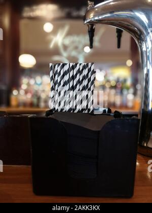 3/4 une pinte de bière contre un arrière-plan flou avec la source et des pailles à la Banque D'Images
