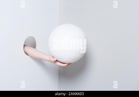 La main dans le trou. Un enfant part détient un ballon de volley-ball blanc et gris sur fond blanc Banque D'Images