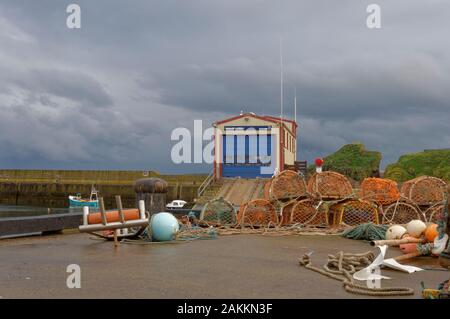 Station de Sauvetage de St Abb's sur le bord du quai de la petite ville de port avec un seul petit bateau de pêche amarré contre le mur du port. Banque D'Images