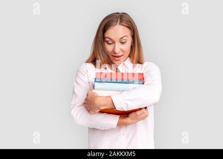 Freestyle. Jeune femme debout étudiant isolé sur blanc avec des livres à la surprise vers le bas Banque D'Images