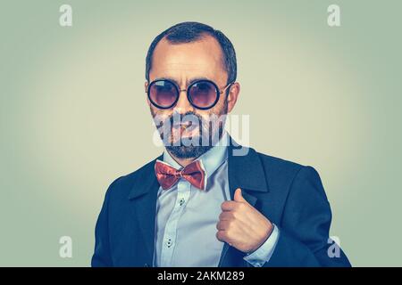 Portrait confiant, riche, homme barbu avec des lunettes, à la caméra et fumeurs de cigare cubain isolé sur fond vert. Patron arrogant, macho continue Banque D'Images