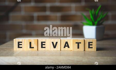 Élever mot écrit sur une cale en bois, concept d'entreprise. Banque D'Images
