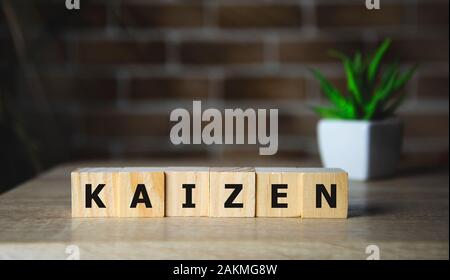 Amélioration Kaizen signe fait de blocs sur un bureau en bois dans une salle lumineuse Banque D'Images