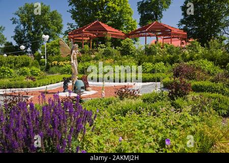 Lythrum salicaire pourpre - fleurs et mythique ailé doré statue fée sur un parterre en forme d'étoile dans Fairy garden au printemps. Banque D'Images