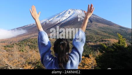 Femme levant les mains saluant la montagne enneigée Banque D'Images