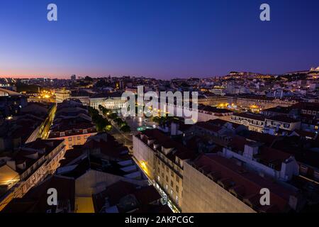 Vue sur la place Rossio (Praca do Rossio), les quartiers historiques de Baixa et d'Alfama et au-delà à Lisbonne, Portugal, dans la soirée. Banque D'Images