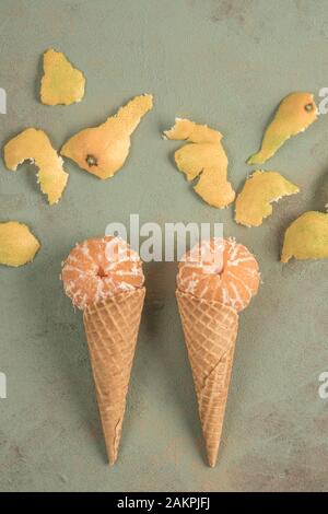 fruits de mandarine dans les cônes de crème glacée sur fond vert avec espace de copie Banque D'Images