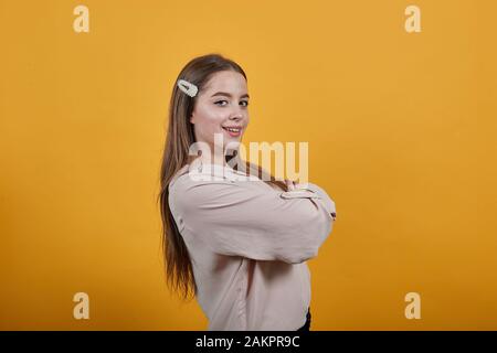 Forte femme dans mode chemise pastel restant sur le côté, laissant les mains croisées Banque D'Images