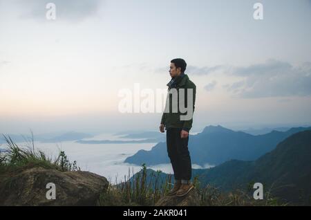 le jeune homme debout sur la colline porte un manteau vert Banque D'Images