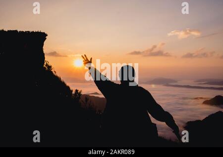 la silhouette d'une femme debout sur la colline est portée à la main dans l'air Banque D'Images