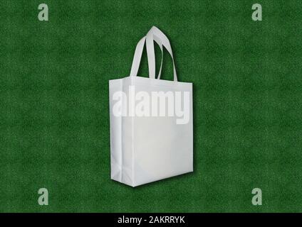 Tissu blanc ECO sac pour l'épicerie et des boutiques sur un fond d'herbe verte. Un exemple de l'emballage qui est sain et respectueux de l'environnement et Banque D'Images