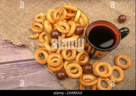 Bagels, petits chocolats, une tasse de thé et un tissu de fabrication locale sur un fond de bois close-up Banque D'Images