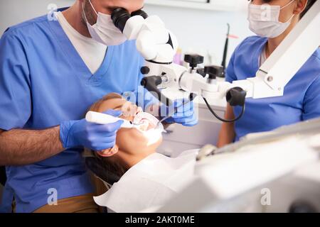 Dentiste à l'aide de microscope et d'examiner les dents de la femme Banque D'Images