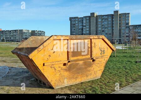 Conteneur en acier vieilli rouillé orange pour la construction et les déchets industriels installés dans un ancien quartier résidentiel de la ville européenne Banque D'Images