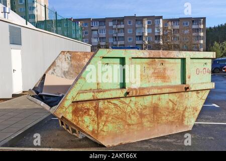 Conteneur en acier vieilli et rouillé vert pour la construction et les déchets industriels installés dans une ancienne zone résidentielle de la ville européenne Banque D'Images