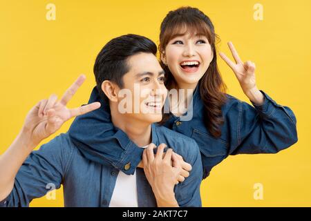 Il et elle voyager ensemble, l'histoire d'amour du beau, heureux, souriant, doux couple en tenue décontractée, les hommes portant son amant sur le dos, femme montrant pea Banque D'Images
