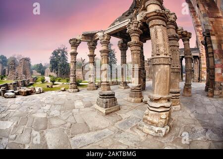 Colonne à Temple en ruines de Qutub Minar à New Delhi, Inde au coucher du soleil pourpre Banque D'Images