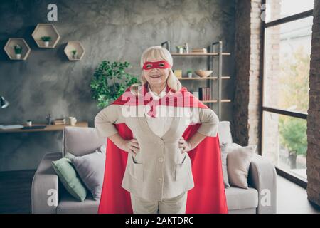 Portrait d'elle belle forte puissante gaie gentille gaie heureuse dame à poil gris portant costume rouge super granny à la mezzanine de brique industrielle Banque D'Images