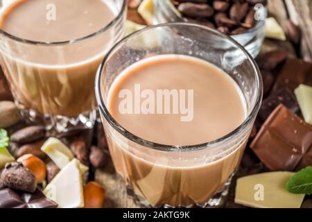 Boisson alcoolisée et forte. Liqueur de chocolat au lait et morceaux de chocolat noir. Espace de copie d'arrière-plan en bois Banque D'Images