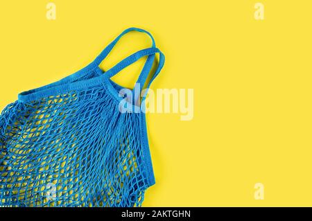 Maillage réutilisable bleu sur fond jaune. Concept écologique. Entretien de l'environnement et rejet du plastique. Pose plate. Banque D'Images