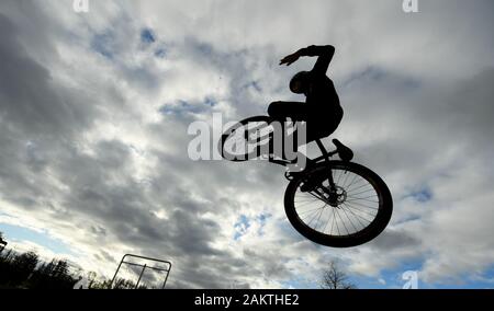 10 janvier 2020, Hessen, Frankfurt/Main : un adolescent saute avec son dirtjump vélo sur la zone du patineur dans le Osthafenpark en face d'un ciel nuageux. Photo : Arne Dedert/dpa Banque D'Images