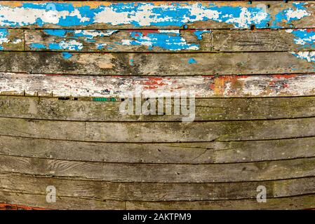 Abstraite de la côté d'un bateau de pêche en bois montrant de nombreuses couches de peinture altérée. Banque D'Images