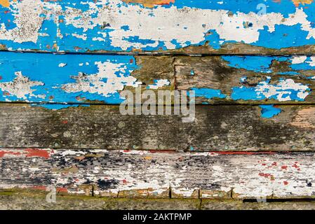 Abstraite de la côté d'un bateau de pêche en bois montrant de nombreuses couches de peinture altérée. Banque D'Images