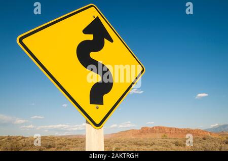 Flèche courbe noir sur jaune lumineux à l'avant de pointage roadsign stark désert paysage Banque D'Images