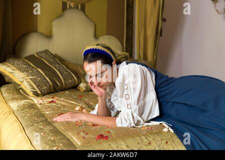 Dutch Master portrait de style d'une belle jeune femme en costume renaissance authentique allongé sur un luxueux lit à baldaquin antique dans une chambre d'or d'un Banque D'Images