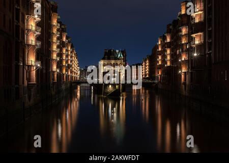 Illuminé Wasserschloss (château d'eau - célèbre bâtiment historique) dans le Speicherstadt (entrepôt) Hambourg après le coucher du soleil pendant l'heure bleue Banque D'Images