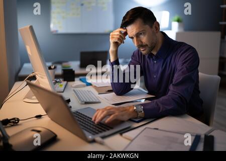 Comptable a souligné assis avec tête en main en travaillant à la fin de l'Office de Tourisme Banque D'Images