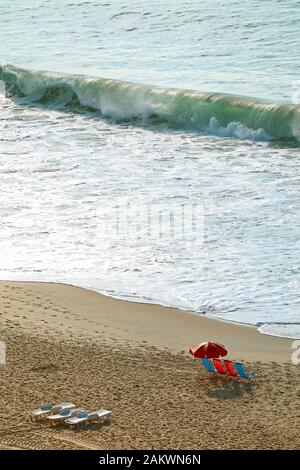 Image verticale de la plage vide avec chaises et parasol et les vagues en crash dans la mer Banque D'Images