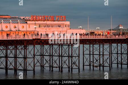 Brighton UK 10 Janvier 2020 - rassembler les foules sur Palace Pier de Brighton pour regarder un coucher de soleil spectaculaire aussi humide et venteux devrait revenir à l'échelle du pays d'ici quelques jours . Crédit : Simon Dack / Alamy Live News Banque D'Images