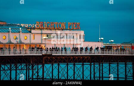 Brighton UK 10 Janvier 2020 - rassembler les foules sur Palace Pier de Brighton pour regarder un coucher de soleil spectaculaire aussi humide et venteux devrait revenir à l'échelle du pays d'ici quelques jours . Crédit : Simon Dack / Alamy Live News Banque D'Images