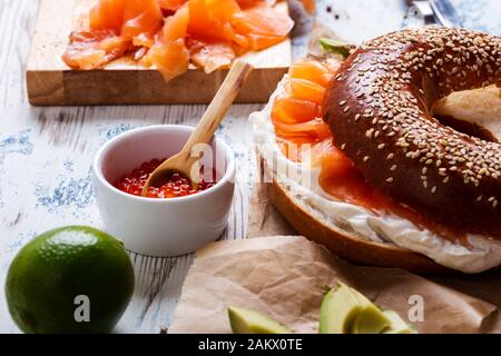 Brunch festif avec saumon fumé servi avec fromage à la crème, bagel, pot de caviar de saumon, avocat, table rustique près Banque D'Images