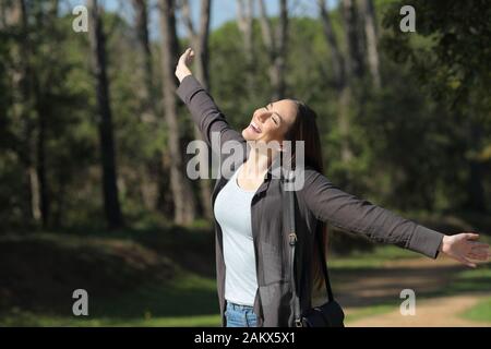 Happy casual woman celebrating new day stretching arms debout dans un parc Banque D'Images