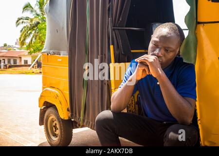 jeune homme africain se sentant triste assis dans un pousse-pousse qui a l'air dérangé Banque D'Images