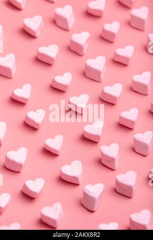 Motif nuage de bonbons en forme de coeur sur fond rose. Image verticale Saint Valentin. Banque D'Images