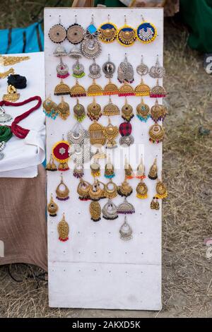 Les boucles d'oreilles traditionnelles indiennes à base de main avec fond flou sont exposées dans une boutique de rue à la vente. Artisanat et art indiens Banque D'Images