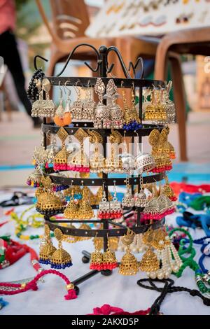 Les boucles d'oreilles traditionnelles indiennes à base de main avec fond flou sont exposées dans une boutique de rue à la vente. Artisanat et art indiens Banque D'Images