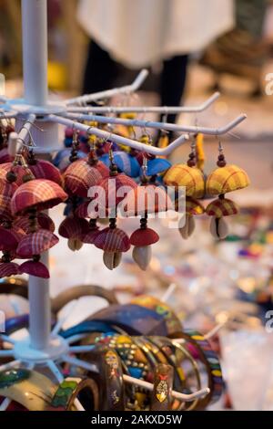 Les boucles d'oreilles traditionnelles indiennes à base de main avec fond flou sont exposées dans une boutique de rue à la vente. Artisanat et art indiens Banque D'Images